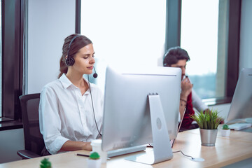 Professional female support staff focused on computer screen, headset communication highlighting efficiency and customer care environment