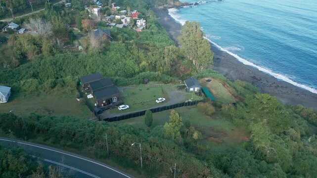 Revealing drone aerial of Niebla black sand beach with white surf, rocky coastline, lush forest, and Pacific Ocean bay panorama