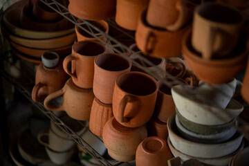 Handcrafted pottery displayed on shelf, featuring various clay mugs and bowls in earthy tones. rustic charm of these ceramic pieces adds warmth to any space