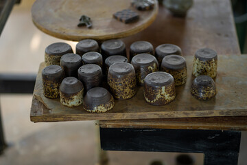 Handcrafted ceramic cups arranged on wooden table, showcasing unique textures and earthy colors. artisanal quality adds rustic charm to setting