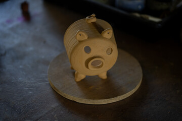 handmade clay pig figurine on wooden base, showcasing craftsmanship and creativity. pig features round body, small ears, and snout, perfect for decorative purposes