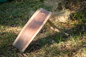 Wooden tool resting on grass, showcasing natural texture and craftsmanship. This rustic item reflects traditional craftsmanship and is set against natural backdrop