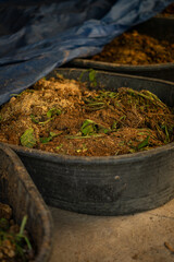 Compost pile in black containers with organic waste and leaves, showcasing process of recycling materials into nutrient rich soil