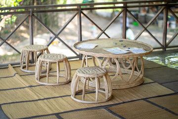 cozy rattan furniture set featuring round table and three stools, perfect for outdoor relaxation. natural materials blend seamlessly with serene environment