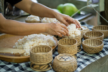 Preparing sticky rice in traditional bamboo baskets, hands skillfully shaping rice. scene captures essence of cultural cuisine and craftsmanship