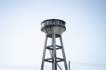 tall, weathered water tower stands against clear blue sky, showcasing its industrial design and structure. scene evokes sense of nostalgia and simplicity