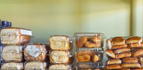 Fresh sweet pastries in a transparent container stand on the shelves of a grocery store