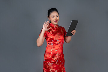 Naklejka premium Modern Asian Woman in Cheongsam Using Digital Tablet