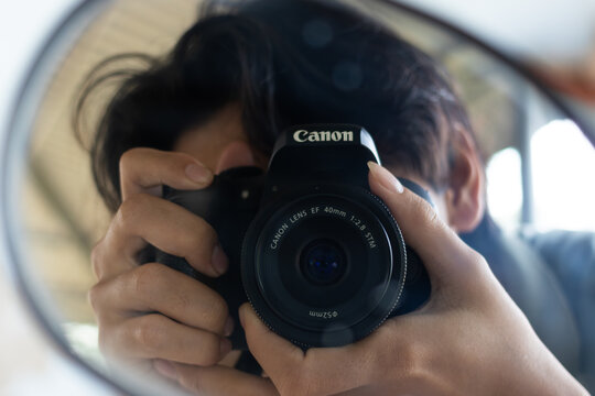 TAN AN, VIETNAM - JANUARY 2, 2026: A photographer takes a mirror selfie using a Canon digital camera equipped with an EF 40mm f/2.8 STM lens