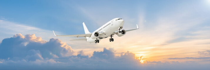 A large white airplane flying ,The background is dominated by a pale azure blue sky, sunset.