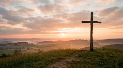 A wooden cross stands on a hill during a beautiful sunrise