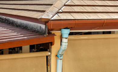 A blue pipe is attached to the roof of a house