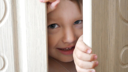 Close-up of a cute boys face peeking out of a closet