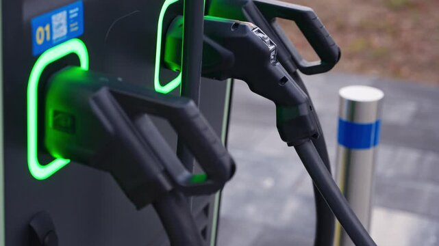 Detailed closeup of electric vehicle charging station with cable plugged in modern urban setting, slow motion