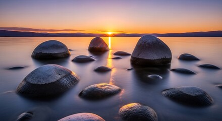 Serene lake scene at sunset with large dark gray stones partially submerged in calm water