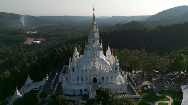 Aerial drone footage of the Loha Prasat Sri Mueang Pong pagoda temple in Chiang Mai, Thailand, on a sunny day, showcasing traditional architecture surrounded by nature.