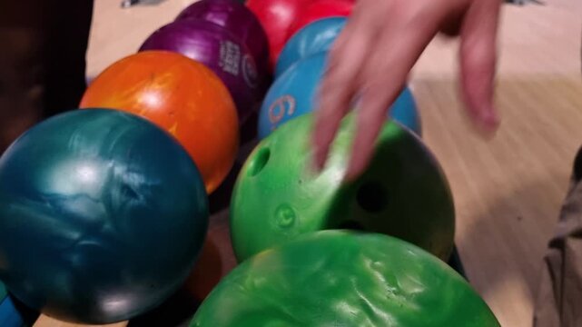 Bright bowling balls rest in a neat row on the return rack inside a bowling alley, just before play starts, setting an inviting indoor leisure mood as players prepare to choose their gear