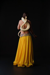 Woman dances with a snake during a performance on a dark stage