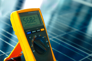 Digital multi meter measuring voltage on solar panel, clean energy concept