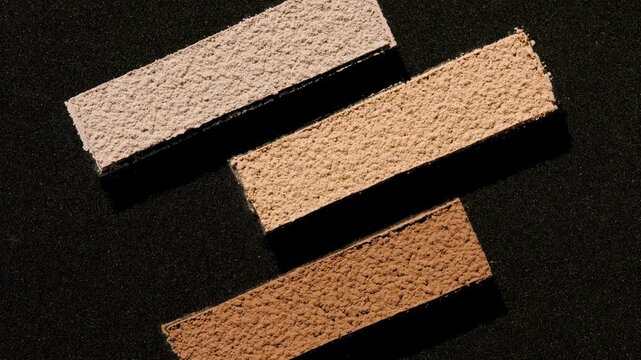 Top view shot of beige and brown powder sifted through a three-stripe stencil with a deep black background | Contour Powder Commercial Concept