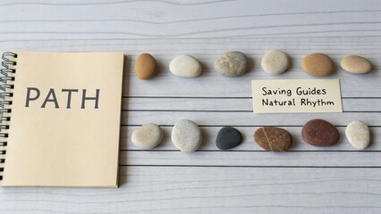 A Visual Representation of a Pathway with Stones and an Open Notebook on a Wooden Surface