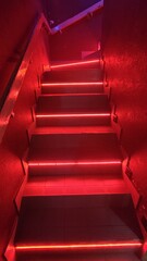 A staircase glowing in red light, adding depth and mystery to the space.