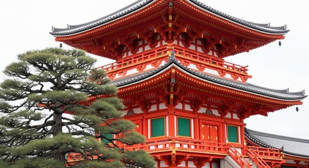 Close-up of a traditional vibrant red East Asian pagoda tower framed by an ancient pine tree.