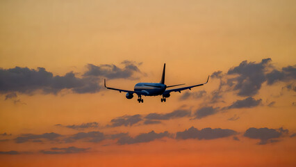 Fototapeta premium Dramatic View of a Jet Aircraft Landing Against an Orange Twilight Sunset Sky