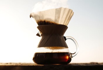 Artisanal drip coffee brewing with paper filter and rising steam in warm light