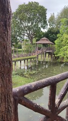 Park Bridge and Gazebo. A peaceful wooden bridge leading to a gazebo surrounded by calm waters and lush trees.