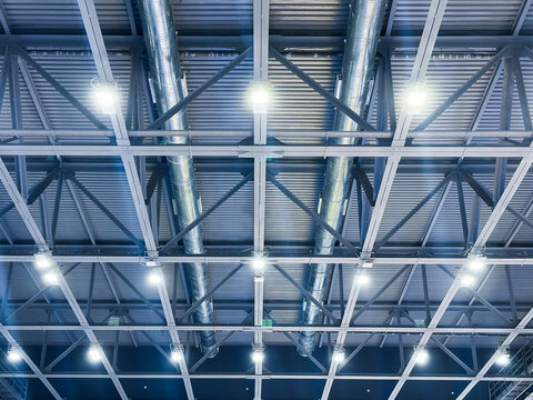 Industrial ceiling with metal beams and bright lights.