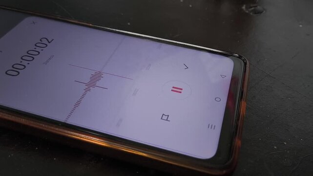 A woman's hand turns on the recording on a voice recorder on the phone. Audio recording for testimony