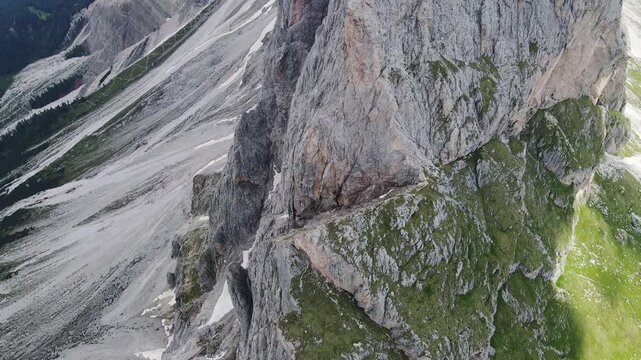 Smooth cinematic drone tilt reveals steep alpine rock faces Seceda Italy