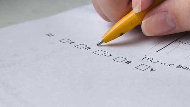 A woman's hand holds a pen and thinks about which answer to choose in the exam test. The process of exams in schools, universities, colleges. Training, education