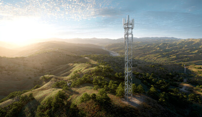 Obraz premium A large, metallic mobile phone tower with multiple antennas and lattice structure situated on rolling green hills under a clear sky during sunset