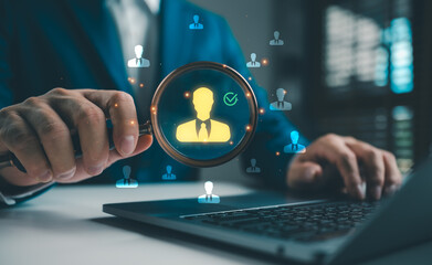 Businessman using laptop and magnifying glass to select employee profile, representing digital...