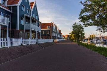Modern waterfront houses with white fences and a promenade in Volendam. Quiet morning by the harbor in North Holland, Netherlands