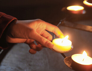 hand girl lighting votive wax candle to pray to her god