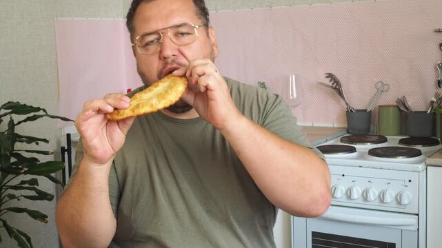 A man eats a cheburek fried in oil.