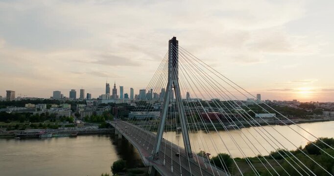 Establishing aerial Panorama of Warsaw skyline above Swietokrzyski Bridge at golden hour. Cinematic riverfront cityscape of Poland Capital with iconic landmarks. 4K drone moving right and upward shot