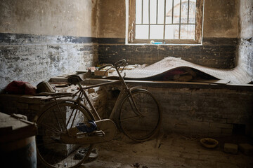 Weathered bicycle left in abandoned building interior with deteriorating walls and window