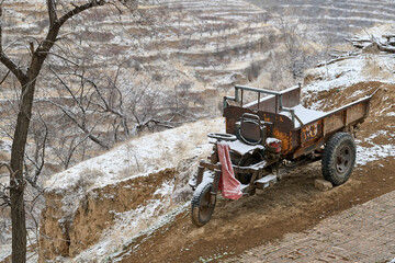 Three-wheeled motorcycle traveling on wet unpaved road through rural village