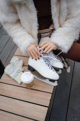 Woman Lacing White Figure Skates on a Wooden Bench