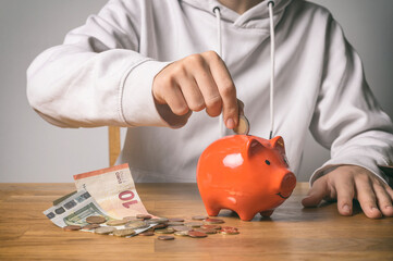 Sparen und Finanzplanung – Person wirft Münze in ein Sparschwein