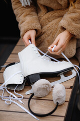 Woman Lacing White Figure Skates on a Wooden Bench