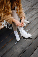  Woman Lacing White Figure Skates on a Wooden Bench