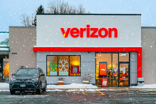 New Hartford, NY - Dec 28, 2025: Verizon, a U.S. telecom company founded in 2000, is shown with holiday signage and snow-covered storefront at retail location during active snowfall