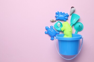 Children's beach toys and seashells on pink background, flat lay. Space for text