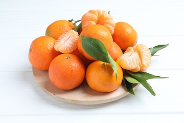 Fresh ripe tangerines with leaves on white wooden table