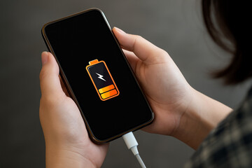 Low battery warning on smartphone held by person, emphasizing need for charging